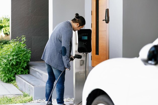 Persona poniendo a cargar su coche eléctrico en casa